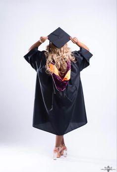 a woman wearing a graduation gown and holding her hat over her head while standing in front of a white background