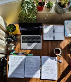 an open laptop computer sitting on top of a wooden desk next to a cup of coffee