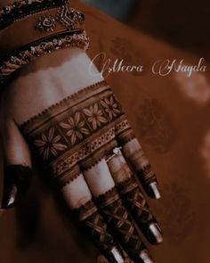 a woman's hand with henna on it and jewelry around her wrist is shown