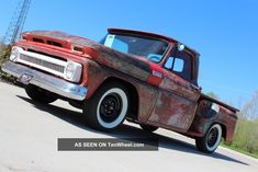 an old red truck is parked on the street