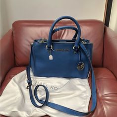 This Michael Kors Shoulder Bag Is A Must-Have For Any Fashion-Conscious Woman. The Stunning Blue Color, Medium Size, And Shoulder Strap Make It Perfect For Everyday Wear. It Also Features Several Pockets And Zippers To Easily Store All Your Essentials. The Bag Is Made Of High-Quality Synthetic Leather And Pvc And Stands Out For Its Beautiful Zipper And Gold Metal Brand. The Michael Kors Collection Brand Ensures That This Bag Is Stylish And Durable. It Is Perfect For Women Who Want Functionality Michael Kors Blue Shoulder Bag For Everyday Use, Blue Michael Kors Shoulder Bag For Daily Use, Michael Kors Blue Bag For Shopping, Blue Michael Kors Tote Shoulder Bag, Blue Leather Michael Kors Bag, Woman Purse, Michael Kors Shoulder Bag, Hand Strap, Michael Kors Collection