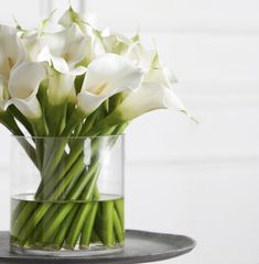 white flowers in a glass vase on a tray