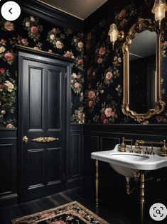 an ornate bathroom with black walls and floral wallpaper, gold trimming on the door