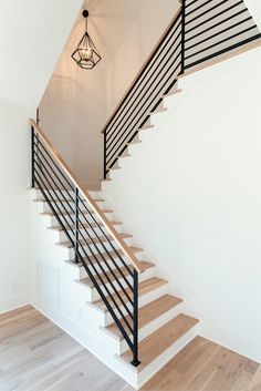 a white staircase with black railing and wood flooring