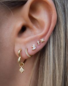 a close up of a person's ear with three stars and moon piercings