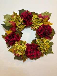 a wreath with red, yellow and green flowers on it is hanging on the wall