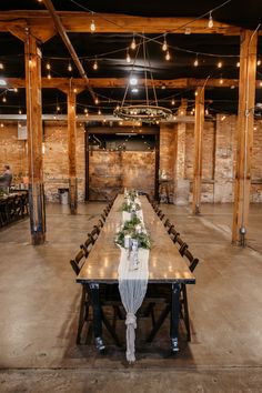 a long table set up with flowers and greenery for a wedding reception in an old warehouse