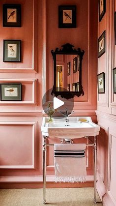 a bathroom sink sitting under a mirror next to a wall with framed pictures on it