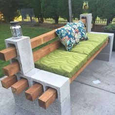 a bench made out of cinder blocks and concrete blocks with pillows on it, sitting in the middle of a sidewalk