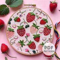 a close up of a embroidery pattern with strawberries on it and other items nearby