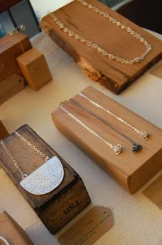 several wooden boxes and necklaces are on a table with white cloth in the background