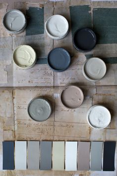 several different colors of paint sitting on top of a wooden table next to each other