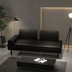 a living room with black leather couches and a lamp on the wall above it