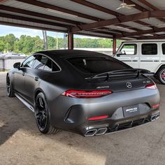 the rear end of a mercedes benz amg coupe parked in a parking lot next to a white suv