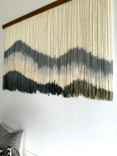 the wall hanging is made from yarn and wood strips, which are hung above a bed