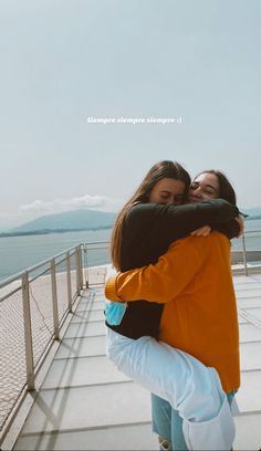 two women hugging each other on a pier