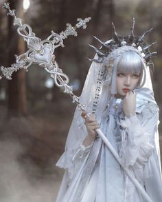 a woman dressed in white is holding a cross and wearing a veil with flowers on it