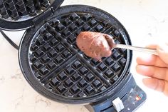 a waffle being dipped with chocolate on top of a pancake maker in the kitchen