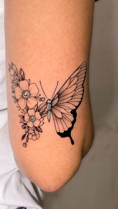 a woman's leg with a butterfly and flowers tattoo on the side of her thigh