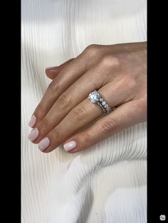 a woman's hand with a diamond ring on her left hand and a white background