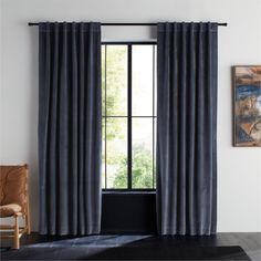 an open window with black curtains and a painting on the wall