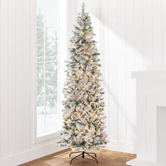 a white christmas tree in a room with wood flooring and large windows on the wall