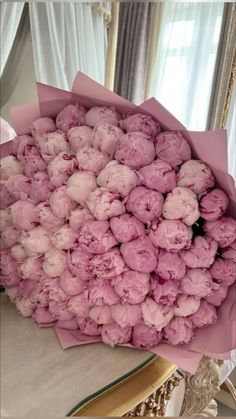 a bouquet of pink flowers sitting on top of a white table next to a mirror