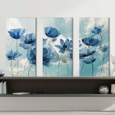 three blue flowers on a white wall in a living room with bookshelf and vase