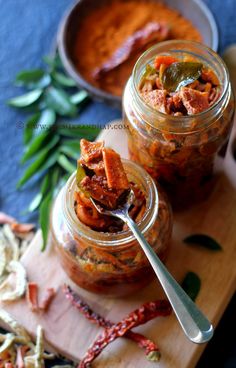 two jars filled with food sitting on top of a wooden cutting board