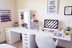 a white desk topped with a computer monitor next to a mirror and drawers filled with makeup