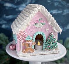 a small pink gingerbread house on a cake plate