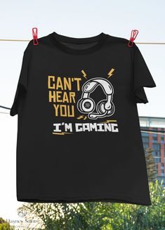 "Product: Can't Hear You I'm Gaming Funny Video Gamer Vintage T-Shirt, Gaming Shirt, Headphone Shirt, Gaming Shirt, Gamer Gift Shirt 💫 Welcome to our store! ✔️ PRODUCTS DETAIL: ▸ Available ALL types of clothing you NEED (8 types from kid to adult, hoodies, sweatshirts, tanktop,..) ▸ Light & Soft cotton fabric (Some colours contain polyester). ▸ High-quality Direct To Garment printing, guaranteed not to wash off or fade. ▸ Fit T-shirts, perfect gift idea for your family, friends... ✔️ SIZING: See size guide in gallery for exact measurements. If you want more of a tight ladies fit, we suggest going down one size. If not, take your normal size. ✔️ CUSTOM AND PERSONALIZED ORDERS: ▸ You can request a custom change on any of our products. ▸ You can give us your idea, and we will make a brand ne Black Gamer T-shirt With Letter Print, Black Gamer Top With Screen Print, Black Short Sleeve Gamer Tops, Black Gamer Top With Funny Text, Black Short Sleeve Gamer T-shirt, Black Gamer T-shirt With Funny Text, Gamer Style Short Sleeve Tops With Funny Text, Gamer Style Cotton T-shirt With Letter Print, Gamer Style Short Sleeve Top With Letter Print