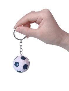 a hand holding a keychain with a soccer ball hanging from it's end