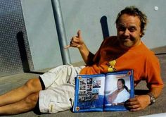 a man laying on the ground with an open book in his lap and thumbs up