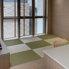 an empty room with wooden blinds and green mats on the floor next to a counter