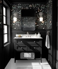 a black and white bathroom with floral wallpaper on the walls, two sinks and a large mirror