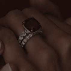 a woman's hand holding an engagement ring with a large brown stone surrounded by small white diamonds