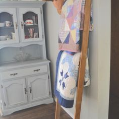 a ladder that is next to a cabinet with towels on it and a towel rack in the corner