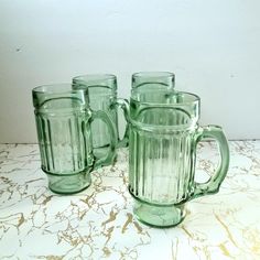 three green glass mugs sitting on top of a counter