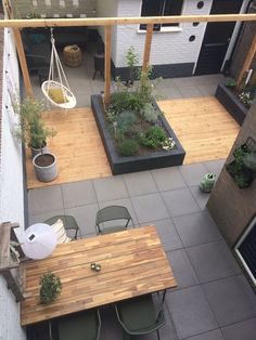 an overhead view of a patio with wooden tables and chairs, potted plants on the far side