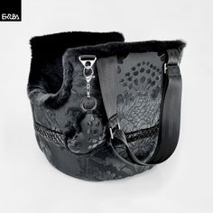 a black purse with an intricate design on the front and side, attached to a strap