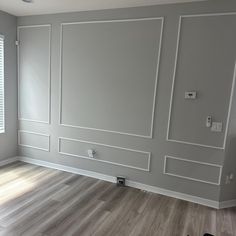 an empty room with hard wood floors and gray walls