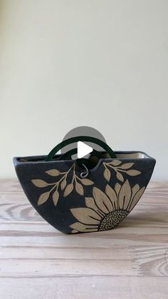 a black and gold flowered bowl on a wooden table