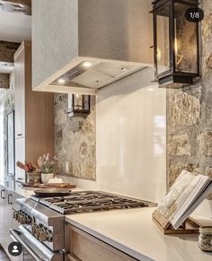 a stove top oven sitting inside of a kitchen next to a wall covered in stone