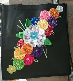 a black bag with many different colored flowers on the front and side, sitting on top of a table