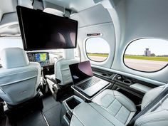 the interior of an airplane with two laptops and a television mounted to the wall