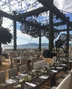 an outdoor dining area with tables and chairs set up on the deck overlooking the ocean