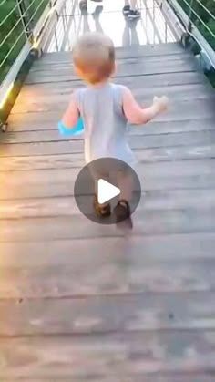 a little boy walking across a wooden bridge