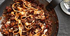 a pan filled with pasta and sauce on top of a table next to utensils