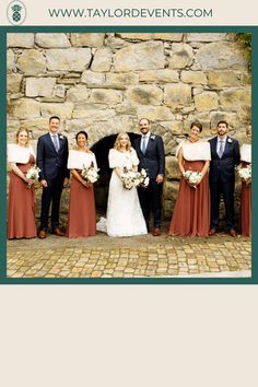 a group of people standing next to each other in front of a stone wall holding bouquets